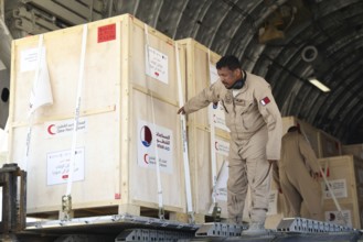 Members of the Qatari Air Force unload humanitarian aid supplies from a transport aircraft at