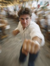 A man gets into a fighting stance, surrounded by dynamic movement and a background filled with