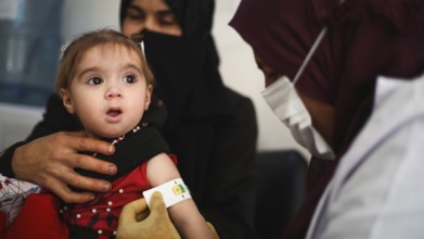 A doctor examines children's malnutrition inside a refugee camp. Malnutrition was measured using a