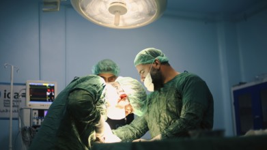 Several doctors performing a complex surgical operation inside an operating room for a displaced