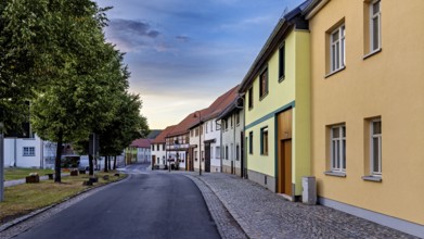 Row of houses in a quiet street with colourful facades and evening sky, the village of Mühlburg in