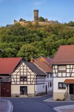 A village with half-timbered houses and a hill with a castle in the background, the ruin Mühlburg