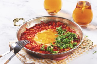 Traditional Turkish dish, scrambled eggs with tomatoes, Menemen, with herbs, in a frying pan,