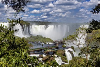 Green jungle and dramatic waterfalls, visitors on a wooden platform, The Iguazu Falls between