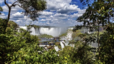 Lush green surroundings, waterfalls in the background, viewpoint with visitors, The Iguazu Falls