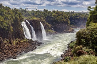 Two waterfalls plunge into a river, surrounded by a green and rocky landscape, The Iguazu Falls