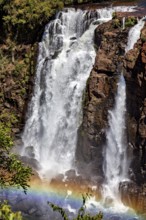 Small waterfall flowing over rocks creates a rainbow in the spray, The Iguazu Falls between
