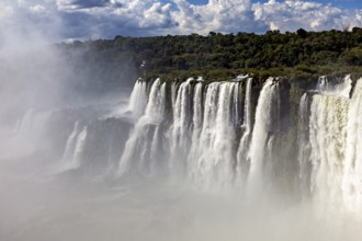 Mysterious waterfalls in the mist, surrounded by a forested area and overcast skies, The Iguazu
