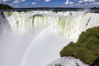 Impressive waterfall with rainbow and spraying spray under a blue sky, The Iguazu Falls between