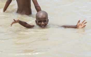 Children bathe in the Brahmaputra River to seek relief from the intense summer heat in Guwahati,