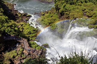 Viewing platform with visitors over a waterfall and rainbow, The Iguazu Falls between Argentina and