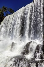 Close-up of a powerful waterfall with splashing spray and rocks under a blue sky, The Iguazu Falls