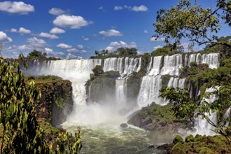 Waterfalls with rich vegetation and spray under a cloudy sky, The Iguazu Falls between Argentina