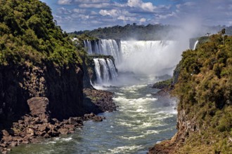 Majestic waterfalls with strong flow and spray, framed by lush vegetation, The Iguazu Falls between