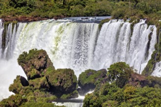 Large waterfall with lush vegetation and rocky ledges, The Iguazu Falls between Argentina and