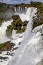 Dramatic waterfall with strong spray, surrounded by green vegetation and rocks, The Iguazu Falls