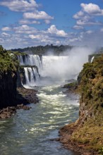 Picturesque view of waterfalls and sky with clouds, lush vegetation and a wide river, The Iguazu