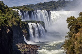 Majestic waterfalls with observation bridge, large river and lush forest backdrop, The Iguazu Falls