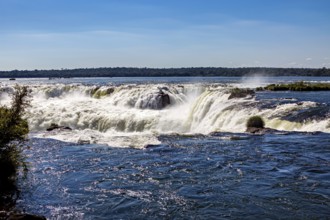 Calm river flows over rapids in bright sunlight, The waterfalls of the Iguazu between Argentina and