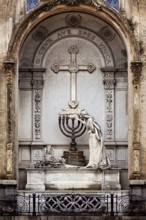 An artistically designed tomb with a statue and a cross in the centre, La Recoleta cemetery in