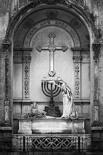 Black and white image of a statue and cross in an ornate mausoleum, La Recoleta Cemetery in Buenos
