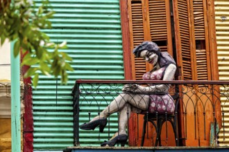 Sculpture of a woman on a balcony in front of a colourful façade, The colourful city and tango