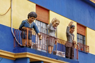 Figures on a balcony of a blue and yellow building in La Boca, the colourful city and tango