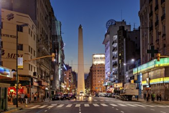 Twilight view of a busy city street, the obelisk illuminated by lights, The great obelisk in the