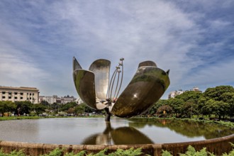 Metal flower sculpture near buildings with a cloudy sky in the background, The lotus blossom in