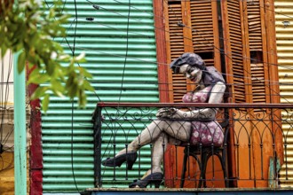Sculpture of a woman on a decorative balcony with a coloured wall, The colourful city and tango