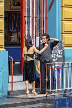 A couple discussing in front of a colourful entrance in tango clothes, the woman wears a black