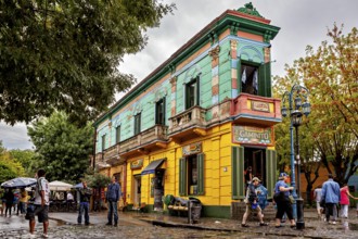 A colourful historic building with cafés attracts people on a cobbled street, The colourful city