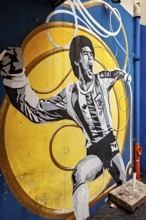 Mural of a cheering football player on a yellow and blue background, The football stadium of La