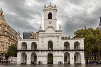 An old colonial style building with clock tower under a cloudy sky in the city, Historic buildings