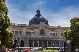 A large railway station with a dome, surrounded by trees and traffic under a blue sky, The city of