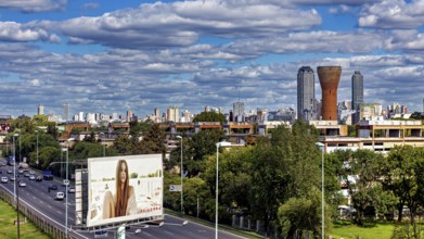 Cityscape with skyscrapers, a large billboard and busy traffic under a cloudy sky, The city of