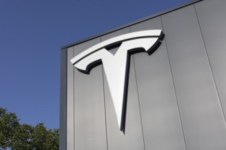 Tesla, logo on modern workshop building, figurative mark without lettering, US car manufacturer for