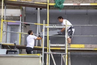 Construction workers insulate a house facade