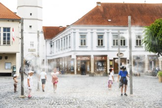Water mist system in the city centre of Trencin, children use the refreshment in the summer heat,