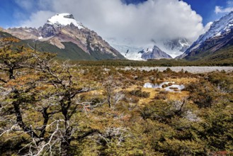Snowy mountain scenery with wild foreland, clouds and a small pond in an autumnal landscape, The