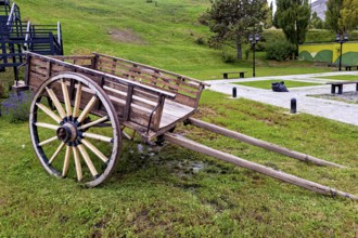 Weathered carriage on a green surface surrounded by hills and trees, Historical horse-drawn