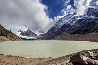 Lake surrounded by snow-capped mountains and glaciers under a cloudy sky, The landscape of