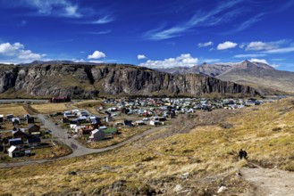 Small village in a barren landscape with high cliffs and blue skies, the village of El Chalten in