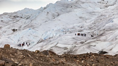Hiking group on a glacier expedition over icy surfaces and boulders, The Perito Moreno glacier in