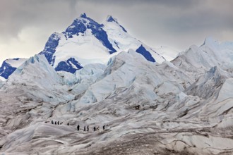 Adventurous climbers on a glacier with looming mountains and clouds, The Perito Moreno glacier in