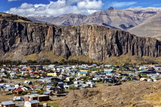 Village with colourful roofs at the foot of impressive cliffs and mountains in the background, the