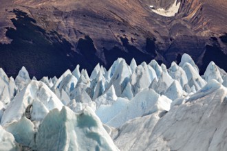 Pointed ice formations in front of a dark mountain landscape with an impressive natural backdrop,