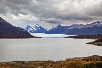 Tranquil landscape with a large lake and glaciers, surrounded by cloudy mountains, The Perito