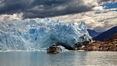 A boat sails close to an imposing, ice-blue glacier front, The Perito Moreno glacier in Argentina