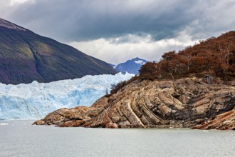 Frozen glacier water meanders between rocks and colourful forests, The Perito Moreno glacier in